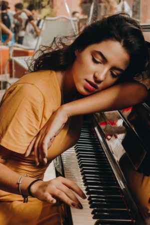 woman lying her head on piano